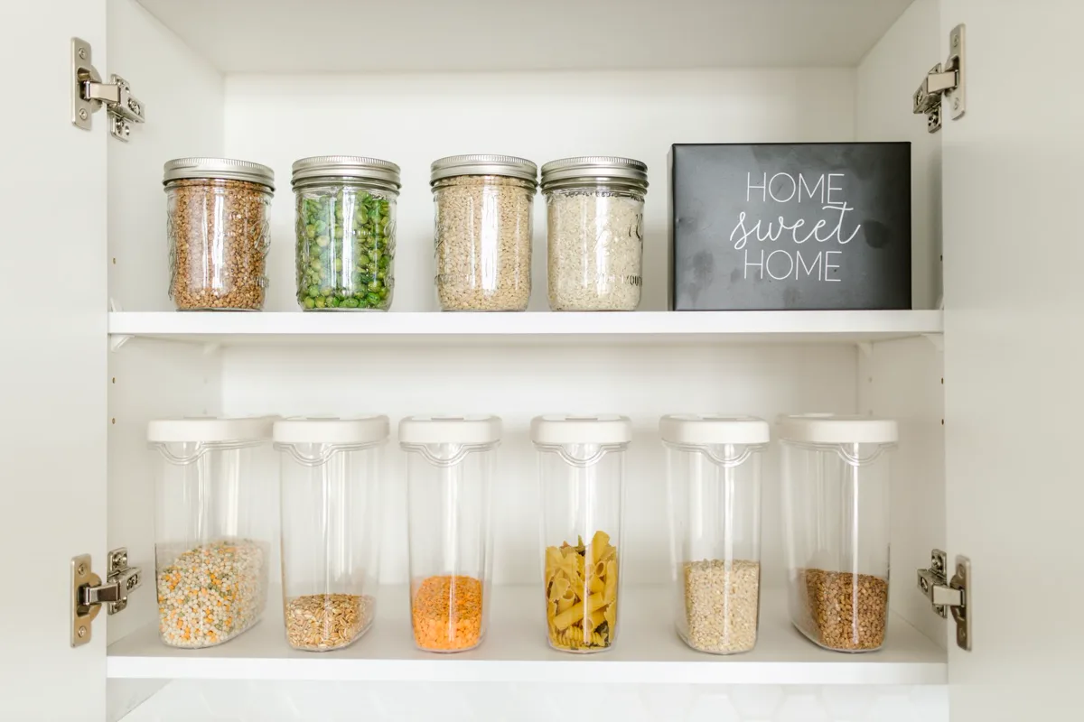 A pantry with labeled jars on two shelves